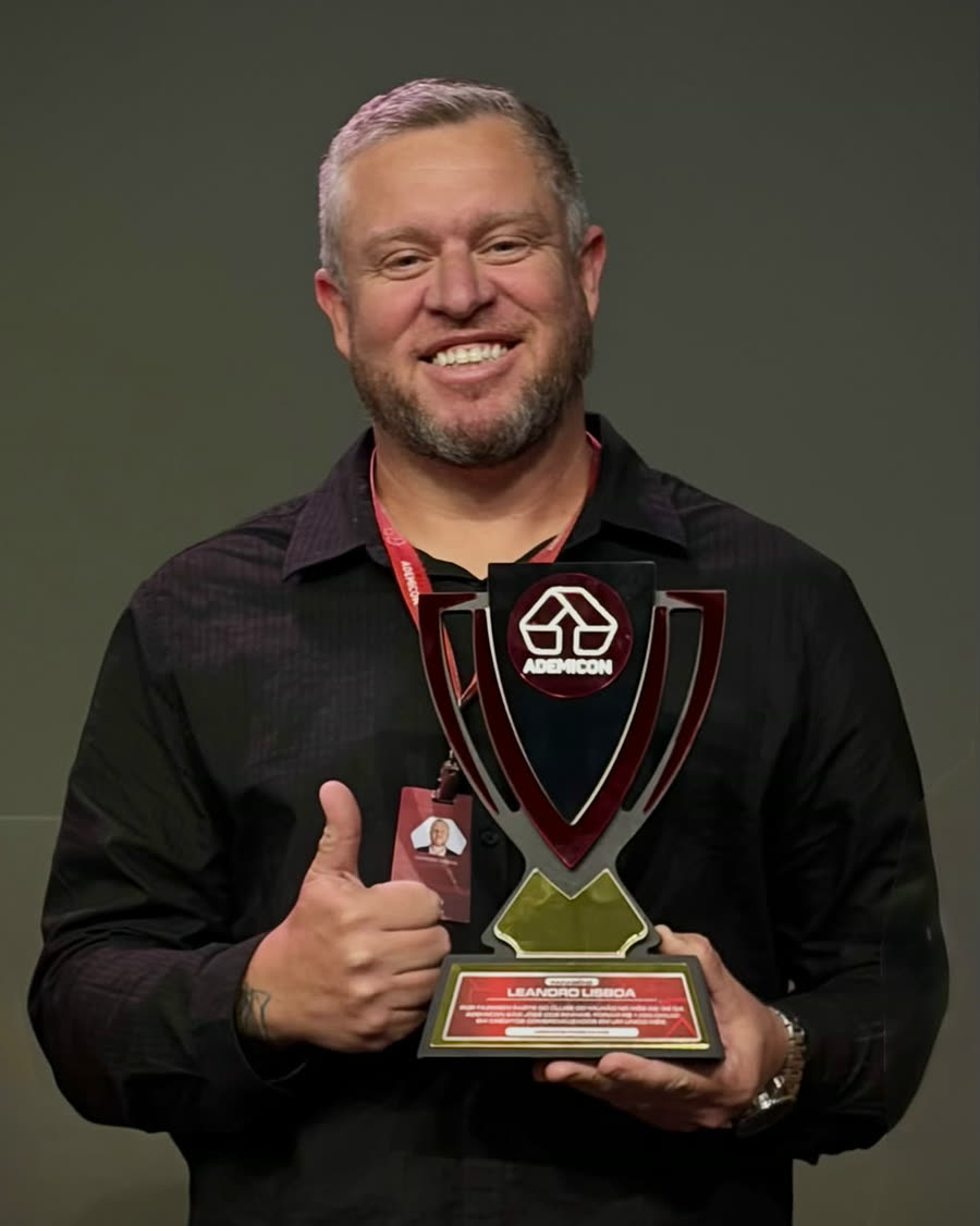 Leandro Lisboa segurando um troféu de reconhecimento da Ademicon